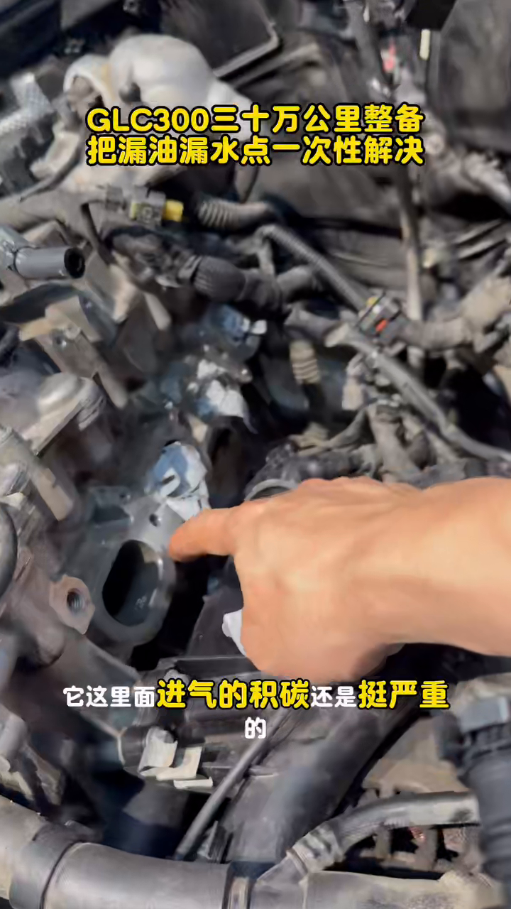 Technician pointing to heater-valve connections in the GLC 300 engine bay