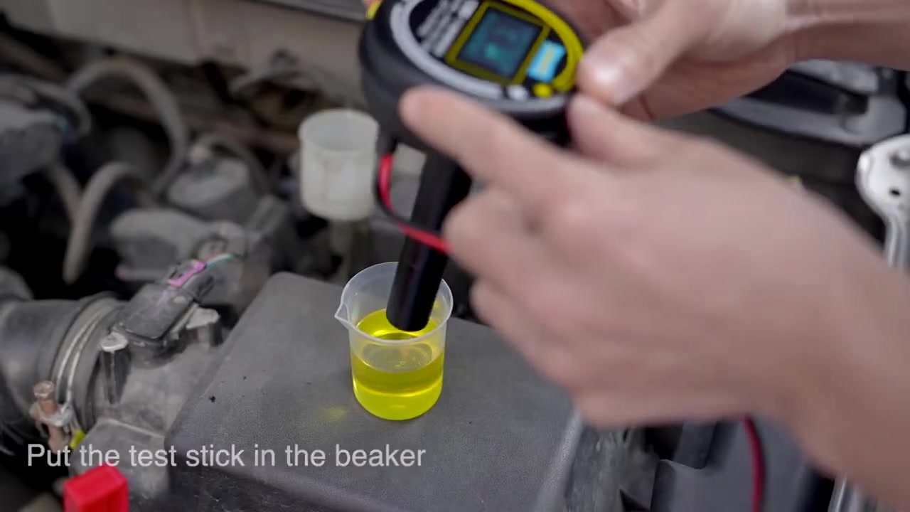 AUTOOL AS506 test stick held vertically in a brake fluid sample beaker