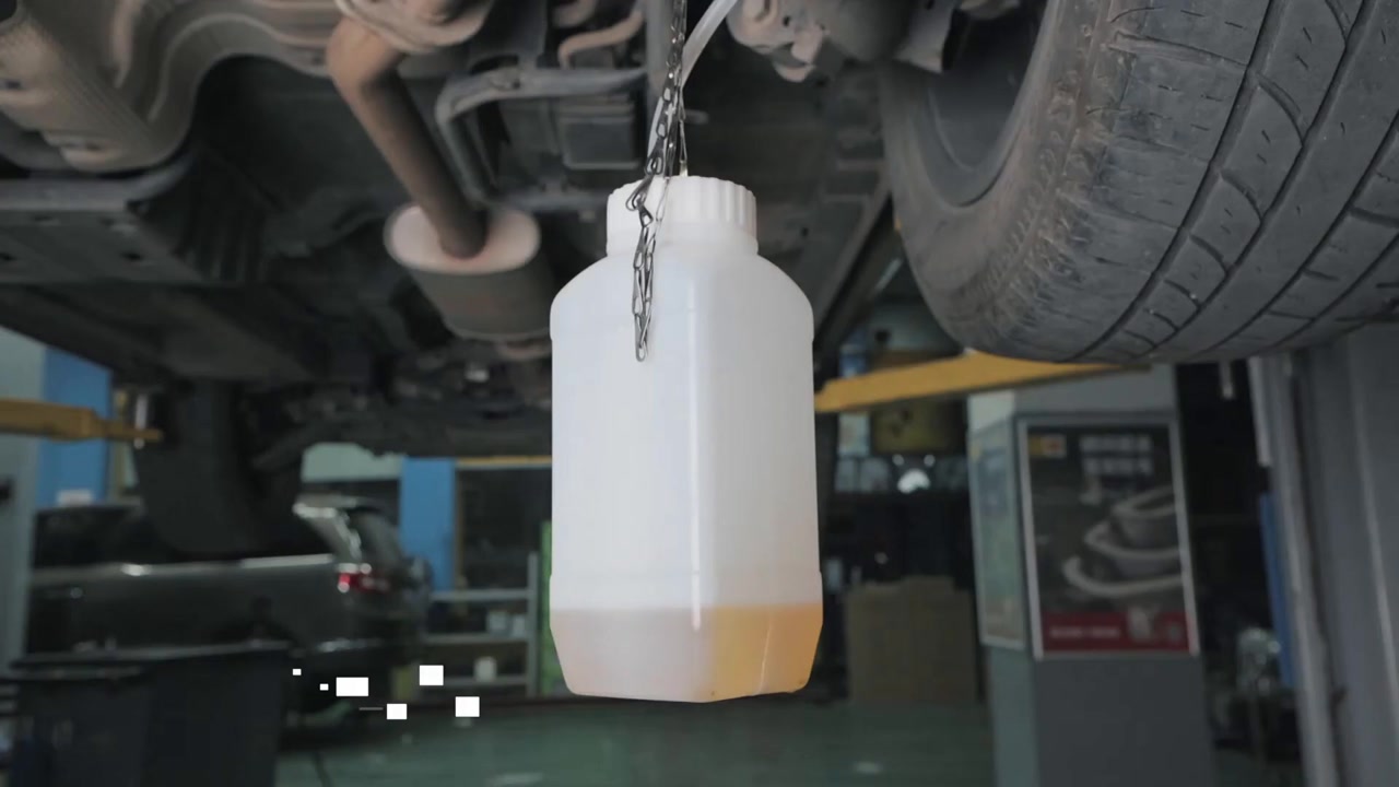 Clear hose routed from one brake service point into a stable used-fluid bottle during AUTOOL AST605 operation.