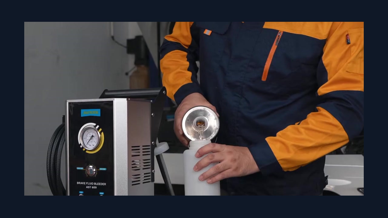 Operator pours brake fluid into the removable external bottle beside a current-panel AUTOOL AST609.