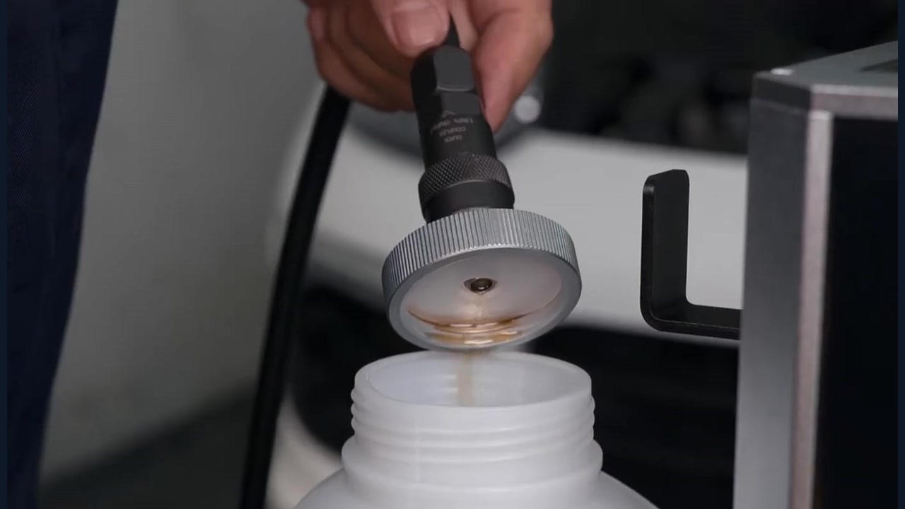 AUTOOL AST609 filling hose and reservoir adapter discharging into a controlled bottle away from the vehicle.