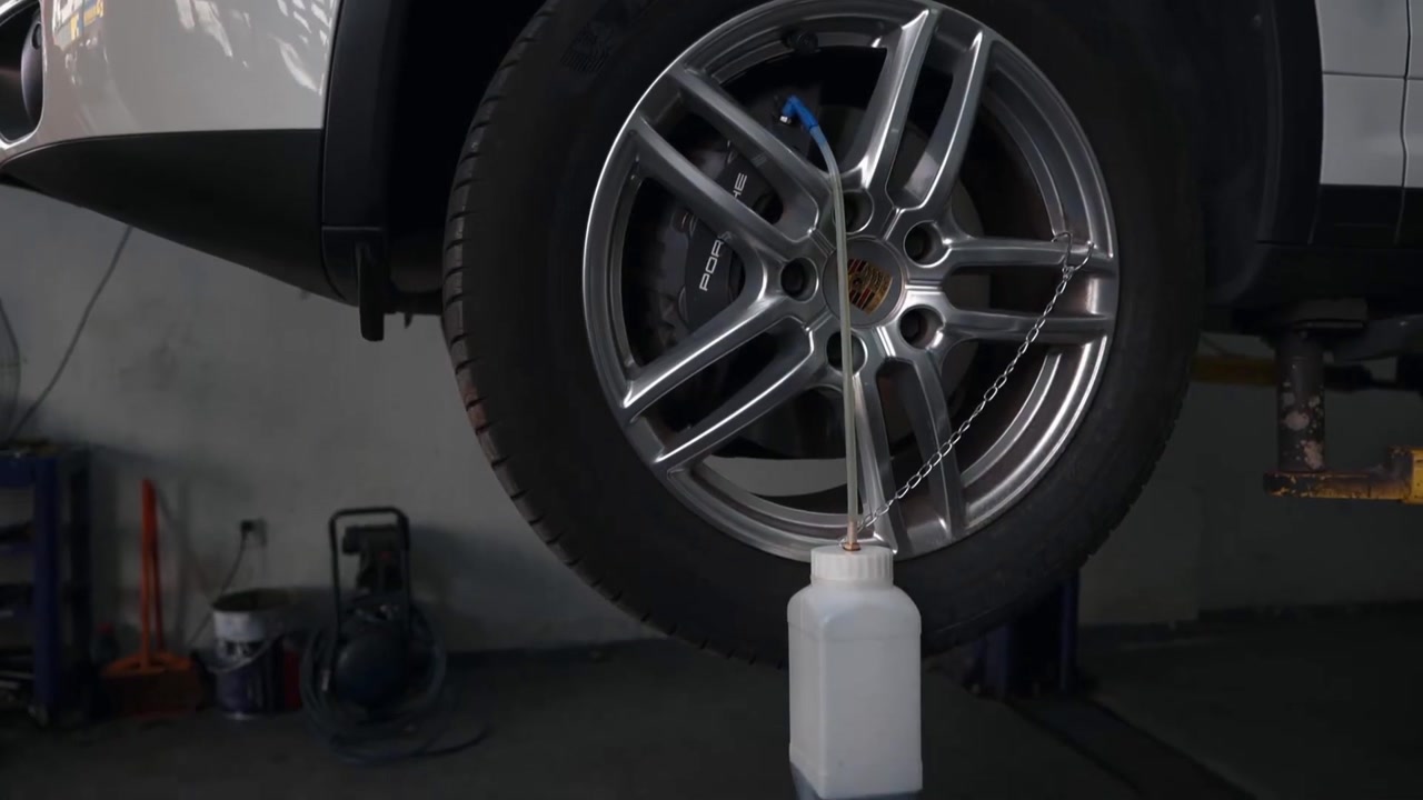 Clear hose routes removed brake fluid from one service point into a stable used-fluid bottle during AUTOOL AST609 operation.
