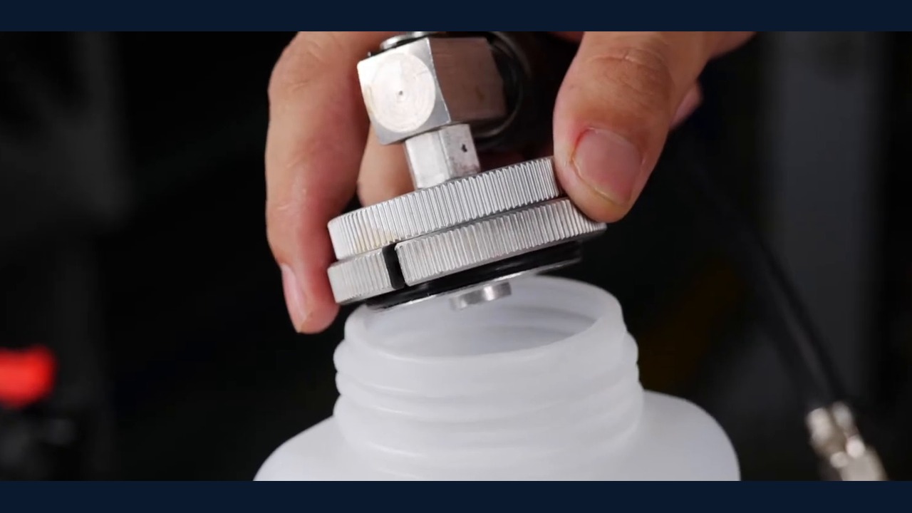 AUTOOL AST618 adapter outlet positioned over a bottle for off-vehicle priming.
