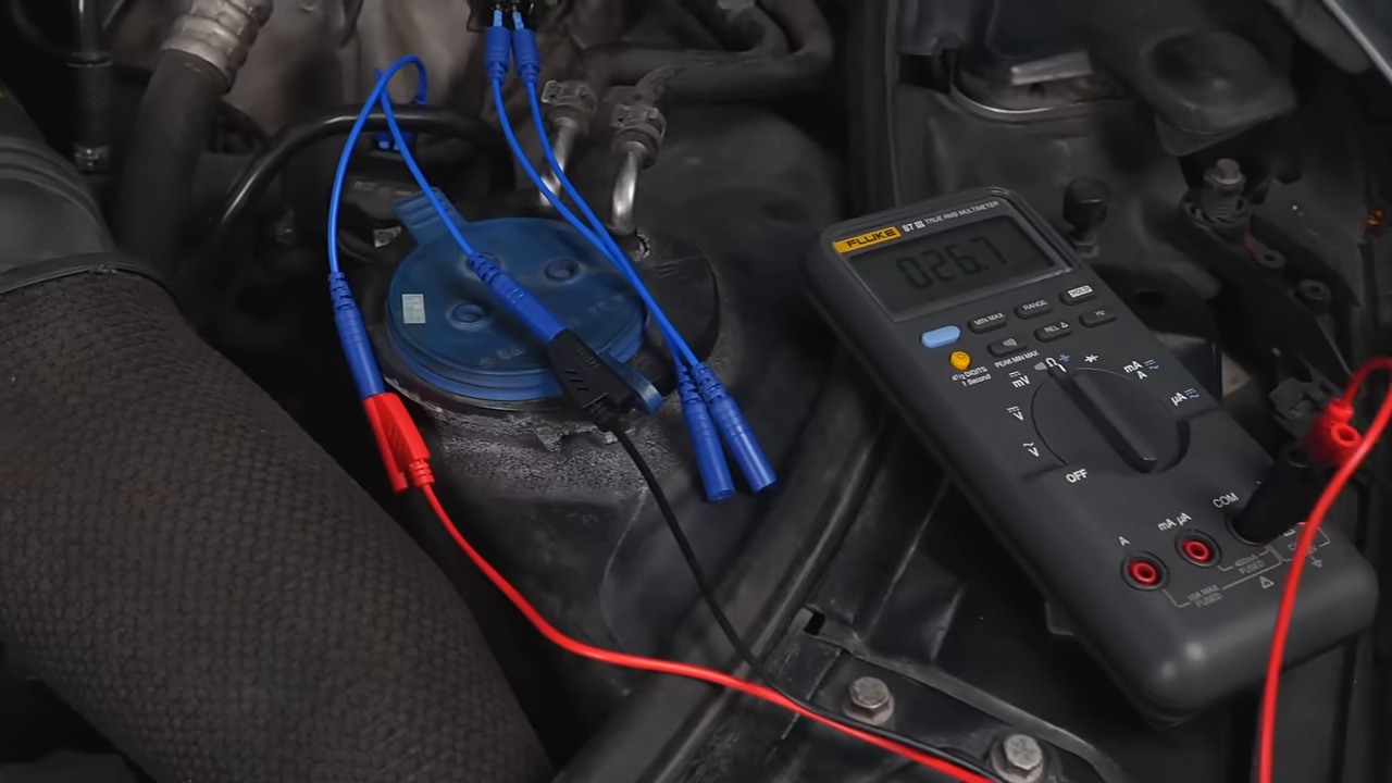 Digital multimeter connected through color-coded AUTOOL test leads during an under-hood electrical measurement.