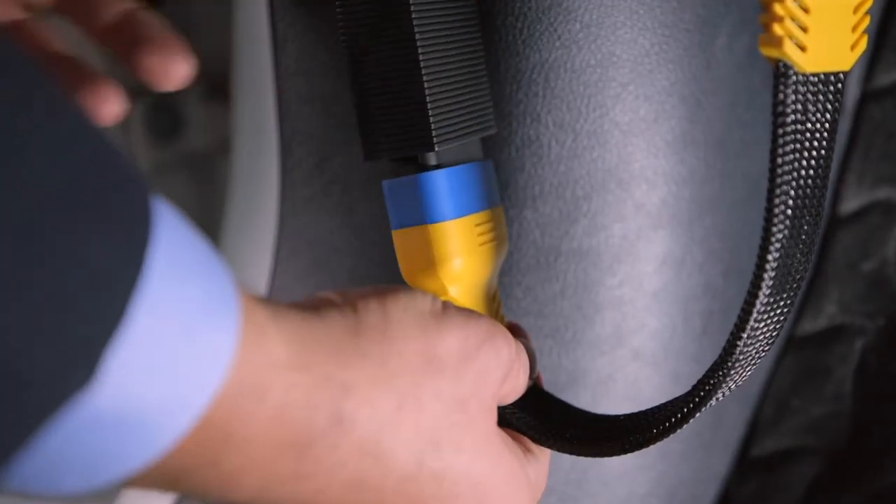 AUTOOL OBD2 extension connector seated at a vehicle diagnostic socket with the cable hanging in a relaxed curve.
