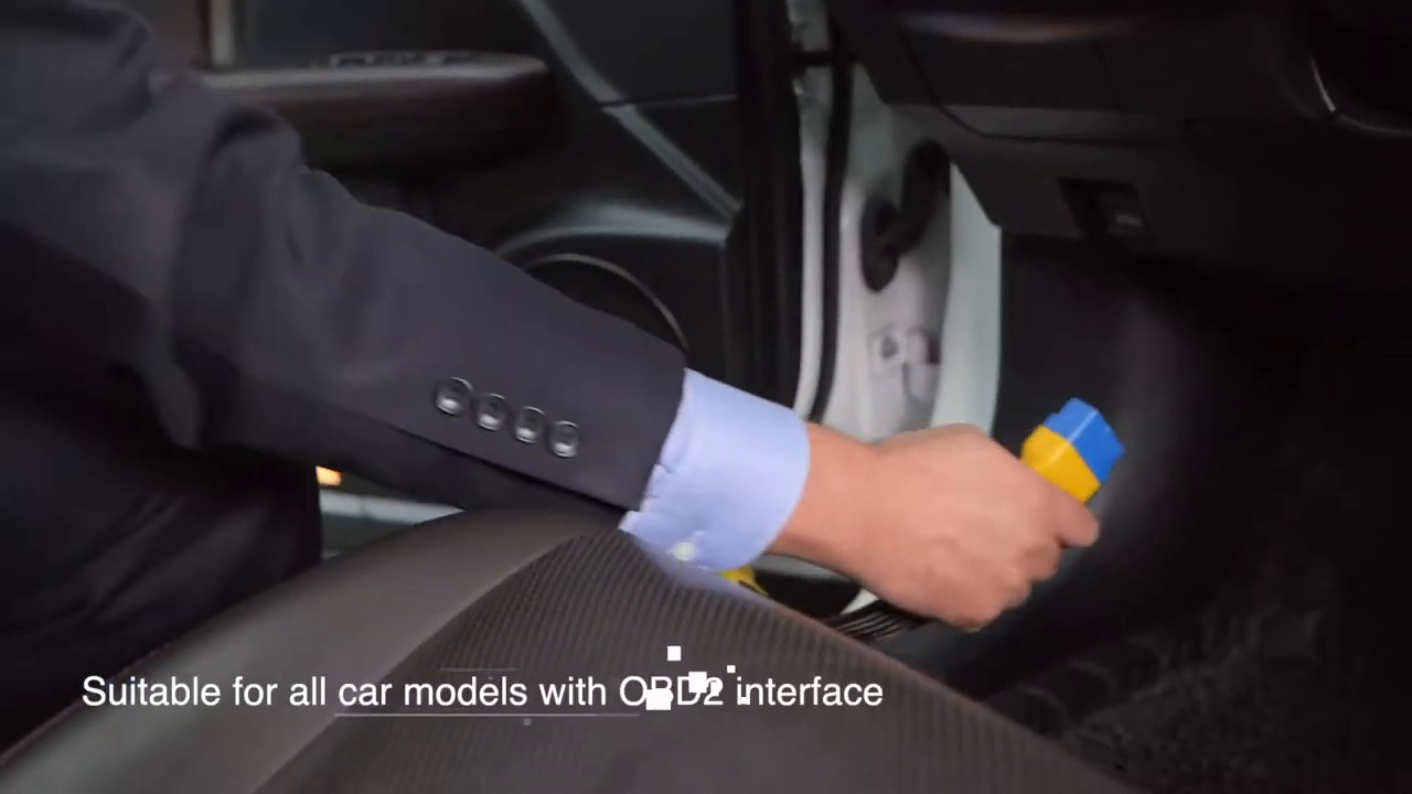 Technician reaching toward a vehicle diagnostic connector under the dashboard with an AUTOOL extension plug.