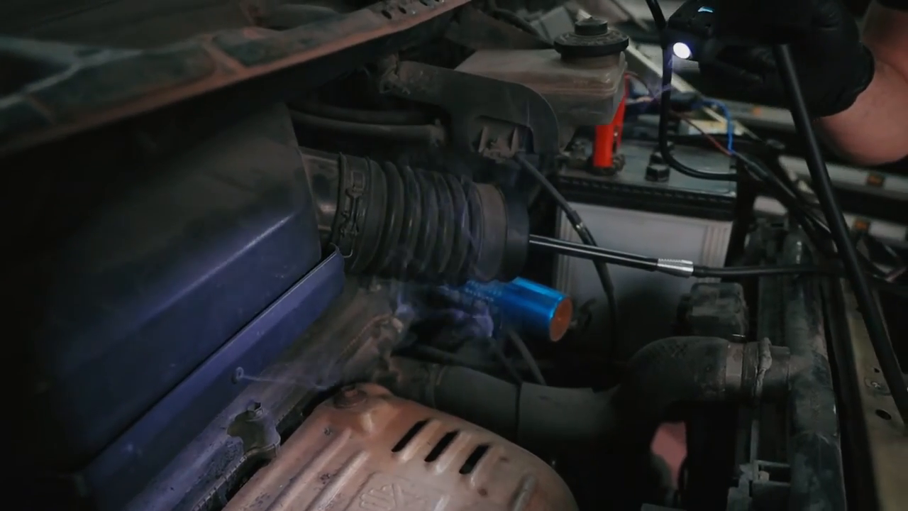 Smoke visible in an engine bay during an AUTOOL SDT206 leak-check demonstration.