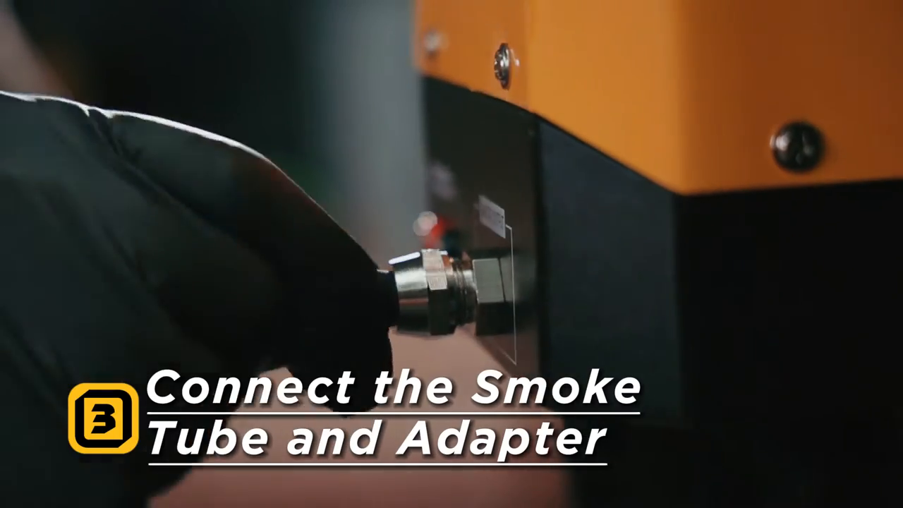 Gloved hand connecting a smoke tube and adapter fitting at an AUTOOL SDT206 machine.