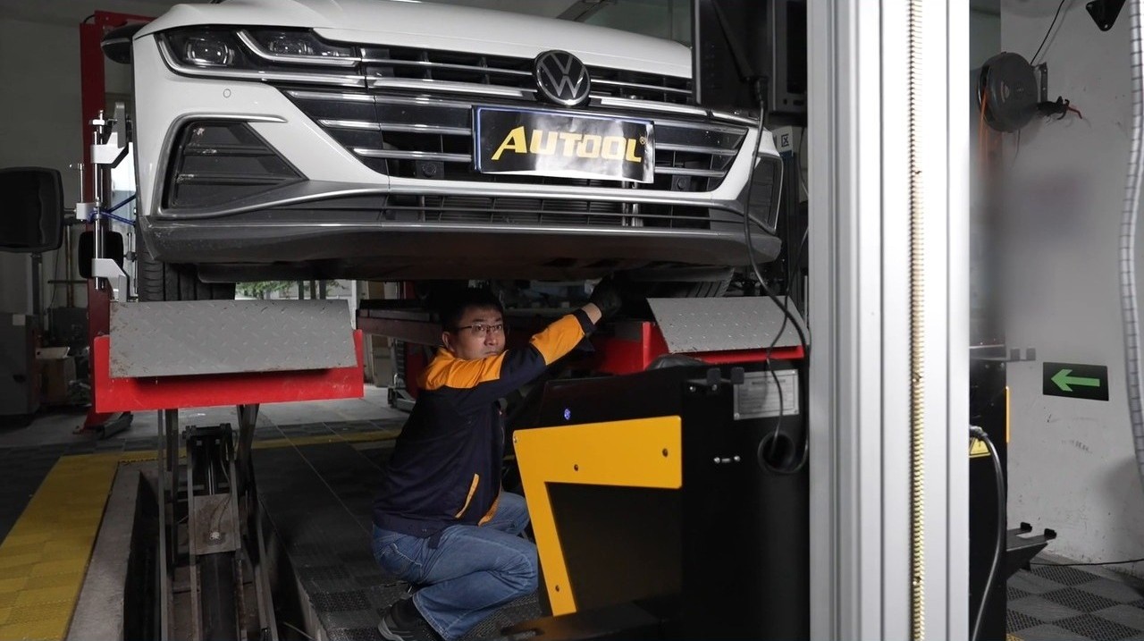 Technician adjusting vehicle suspension on the alignment rack