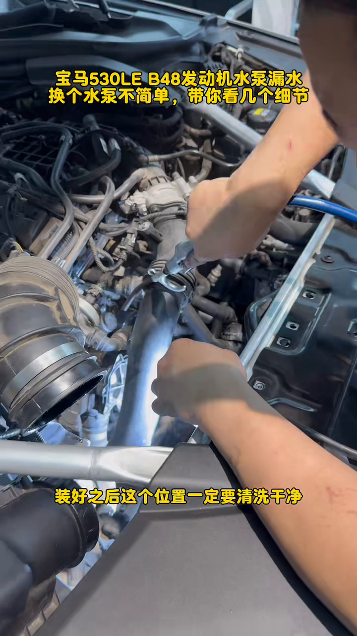 Technician cleaning the BMW B48 water-pump work area after installation.