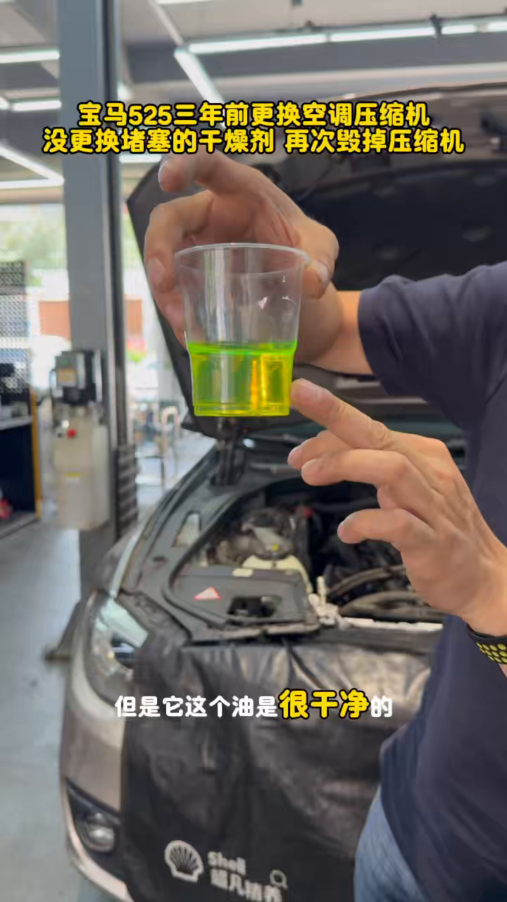 Recovered fluorescent refrigeration oil from the removed BMW compressor in a clear cup.
