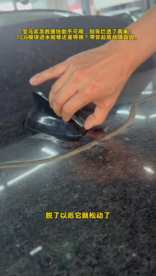 Hand moving the loose shark-fin antenna housing on the BMW roof.