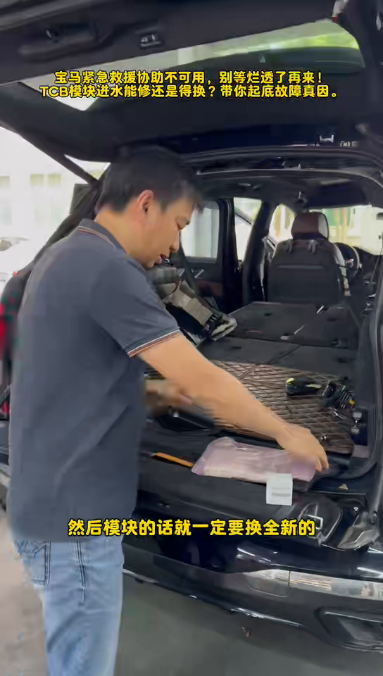 Technician at the BMW cargo opening beside the damaged and replacement TCB electronics.