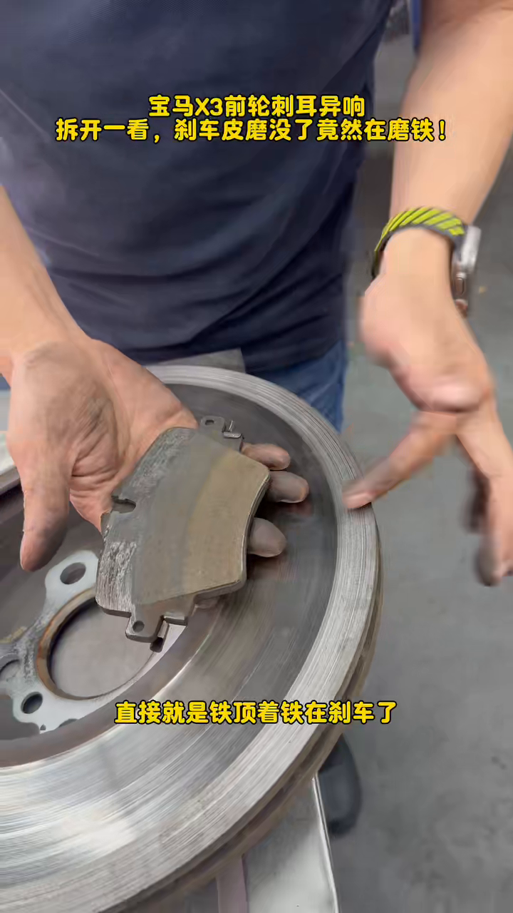 Technician holding the worn inner X3 brake pad against the damaged disc