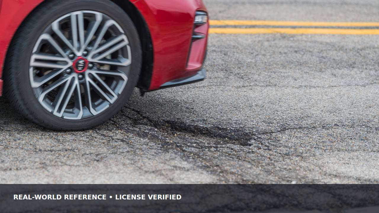 Passenger car wheel approaching a pothole on a paved road