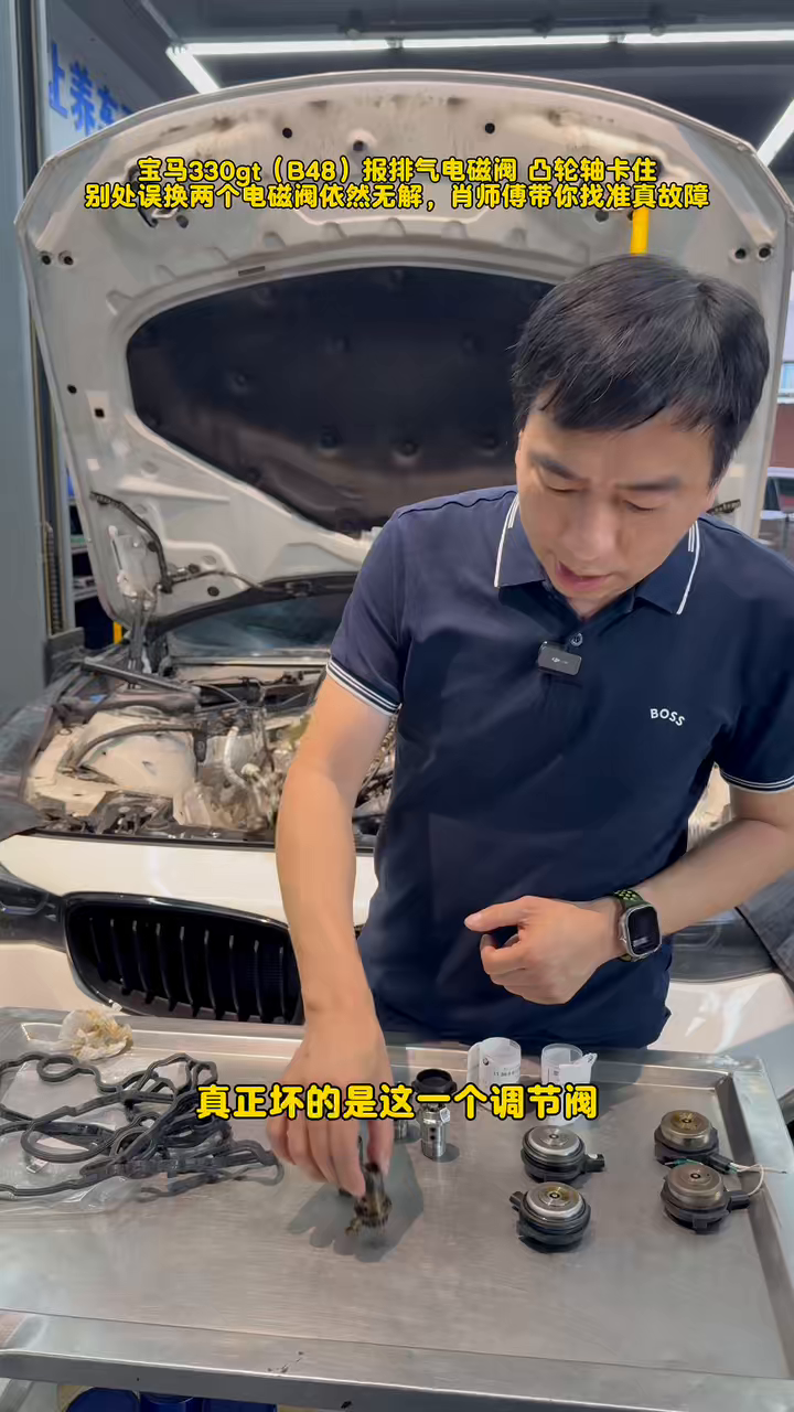 Presenter pointing to the BMW B48 central VANOS adjustment valve among the removed parts