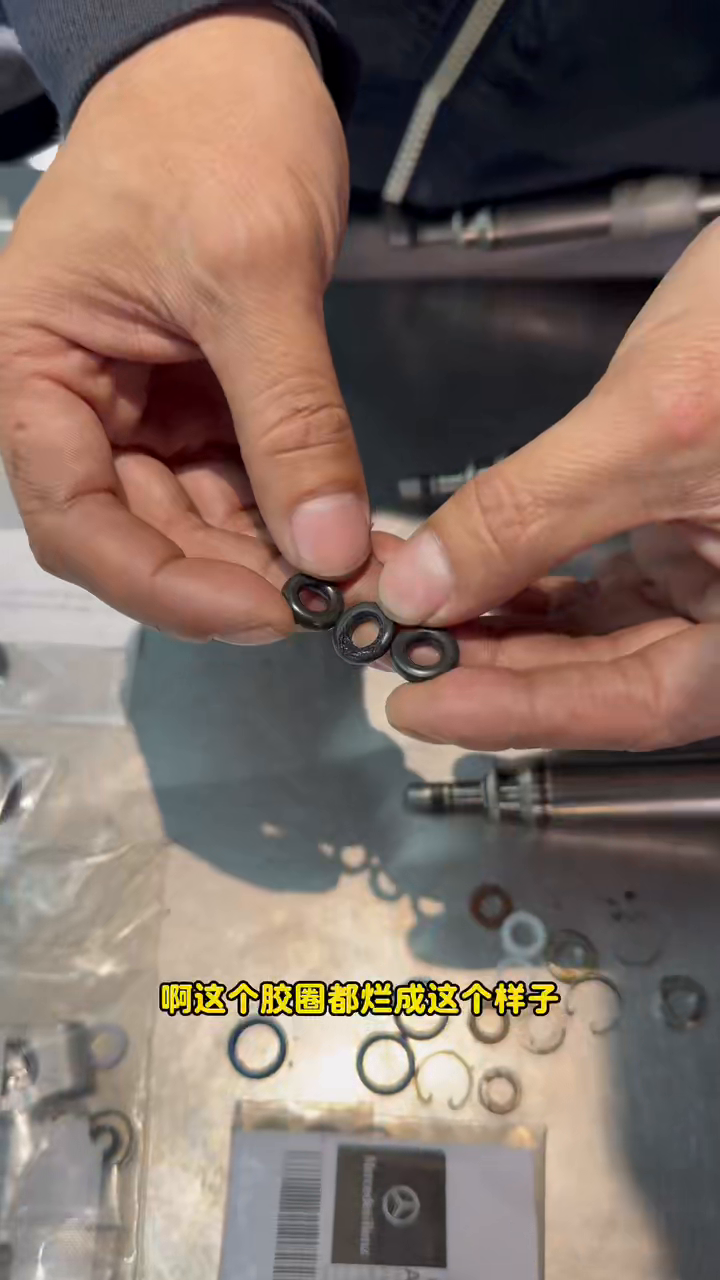 Close view of deteriorated black injector sealing pieces held above the repair parts.