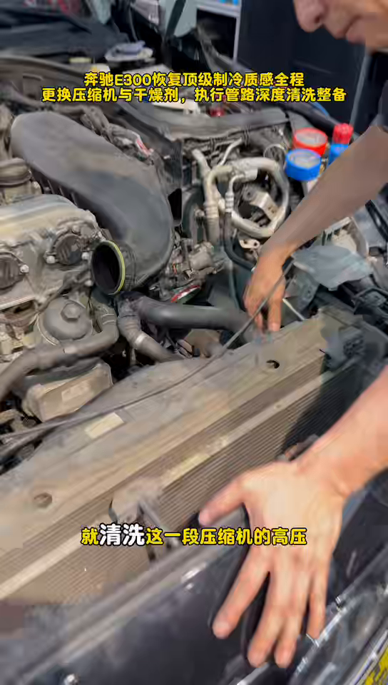 Technician indicating the Mercedes E300 high-pressure A/C circuit and condenser area during cleaning.