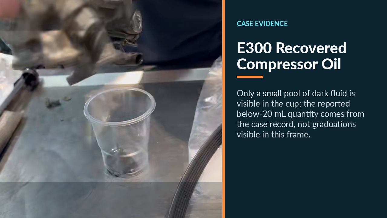 Dark oil draining from the removed Mercedes E300 A/C compressor into a clear cup.