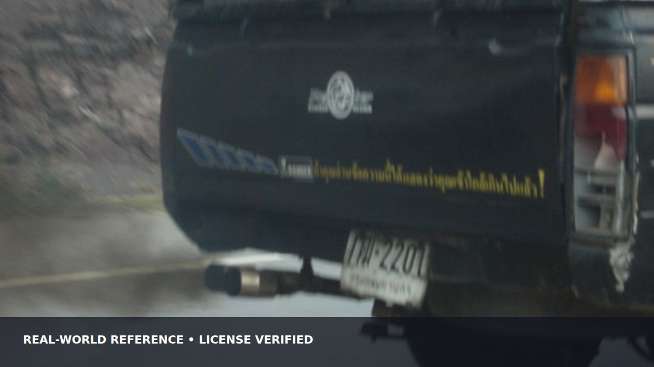Dark exhaust smoke visible behind a passenger vehicle on a road