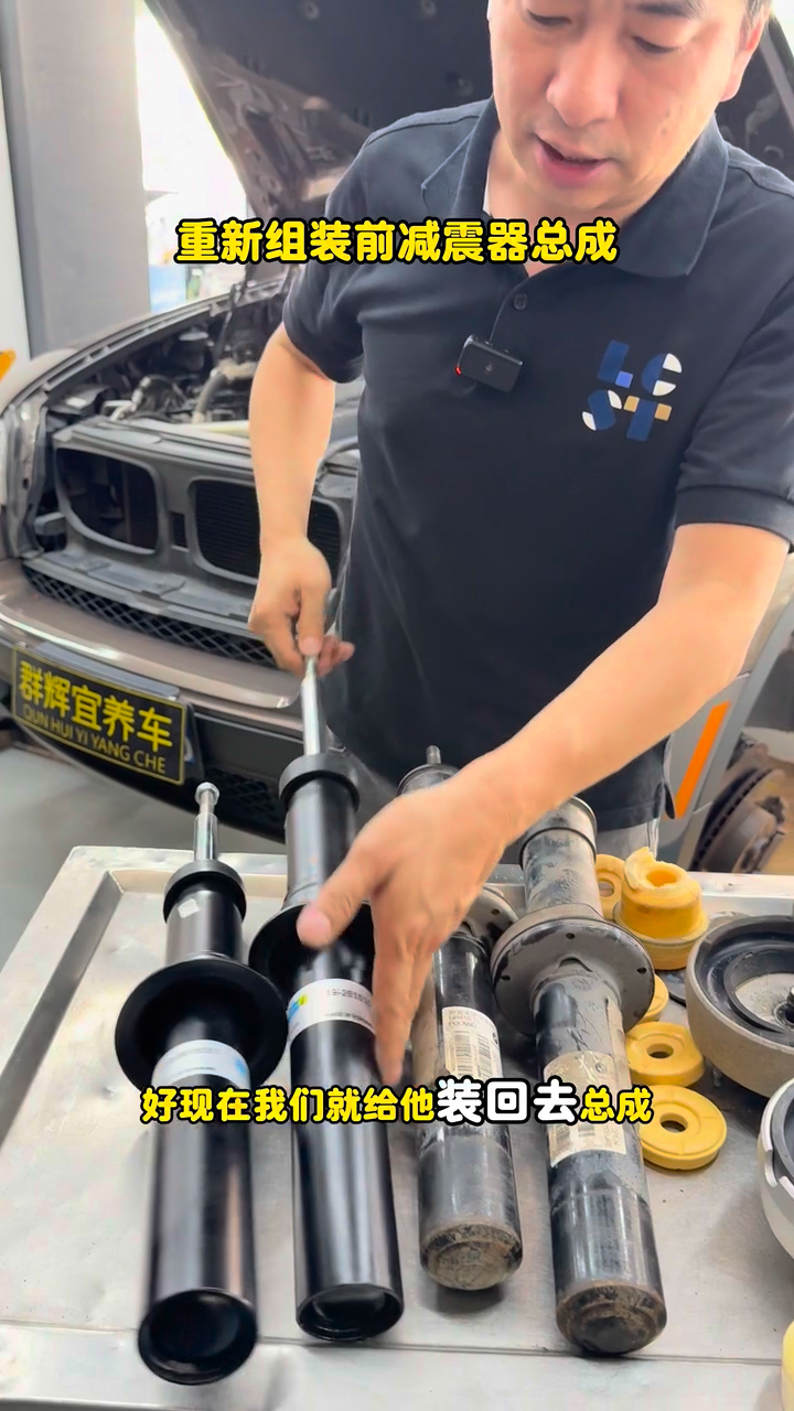 Replacement and removed front dampers laid out during BMW X5 assembly work