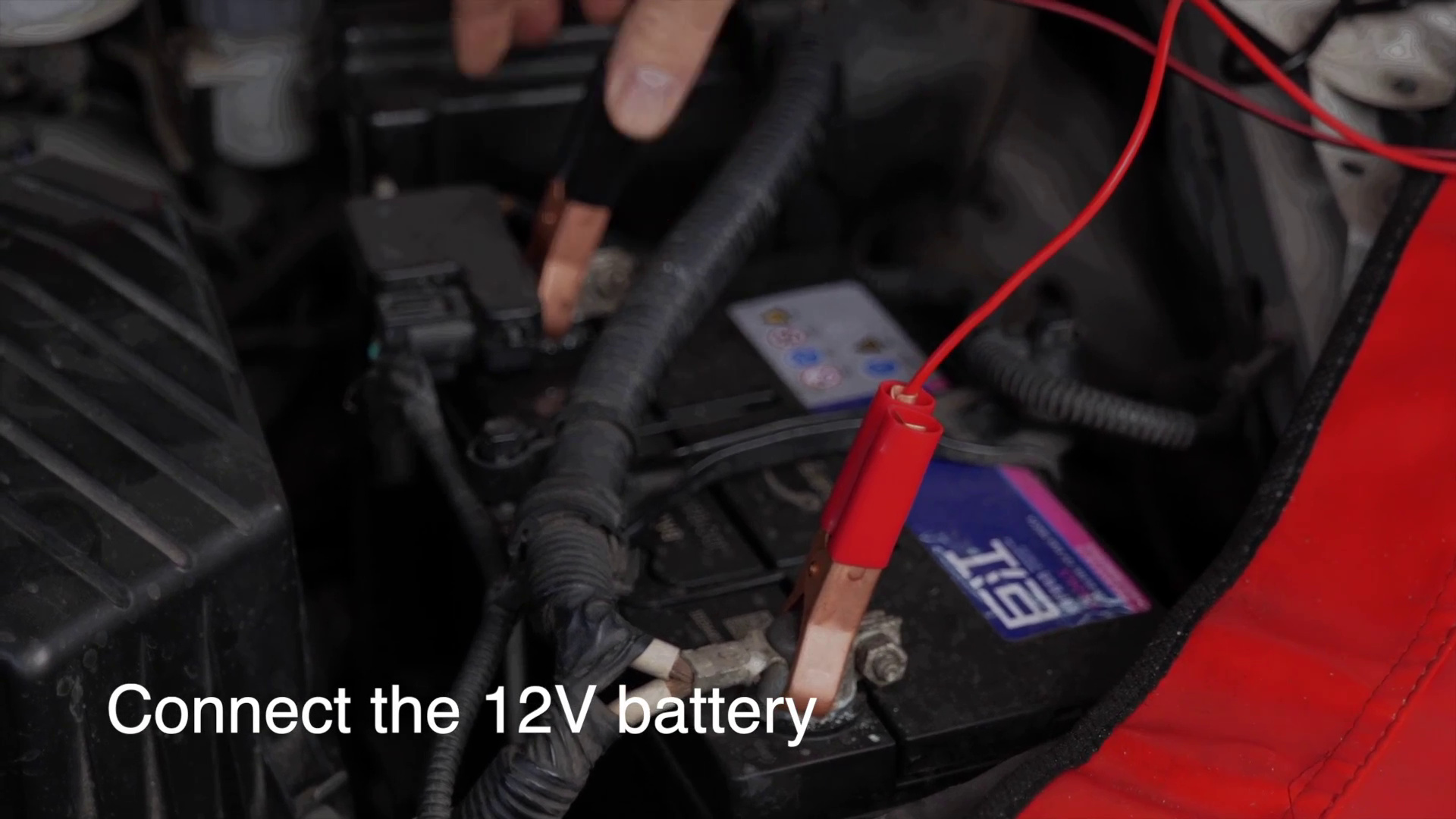 Red and black FXTUL F603 clamps being connected to a 12-volt vehicle battery