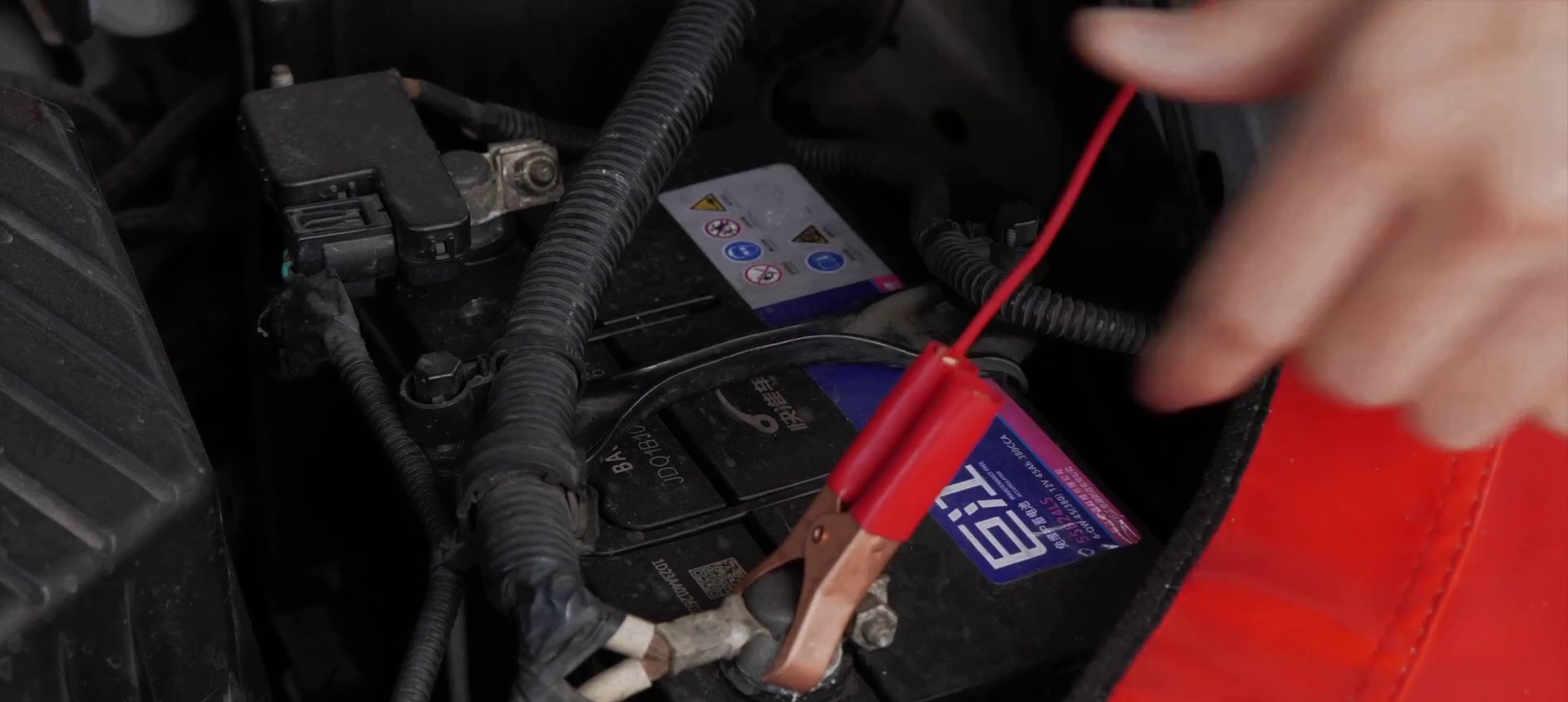 FXTUL F703 red and black clamps connected to a 12-volt vehicle battery
