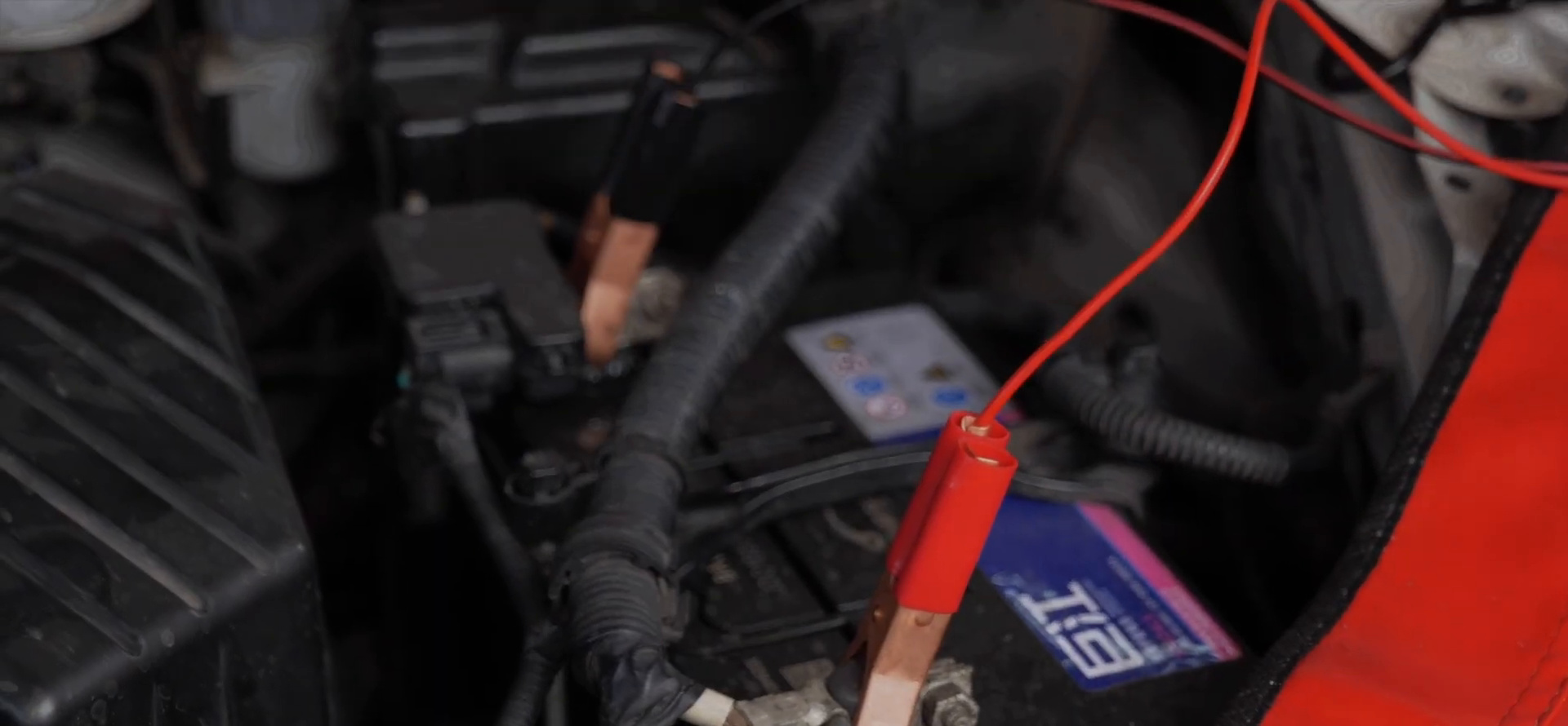 FXTUL F803 red and black clamps being connected to a 12-volt vehicle battery