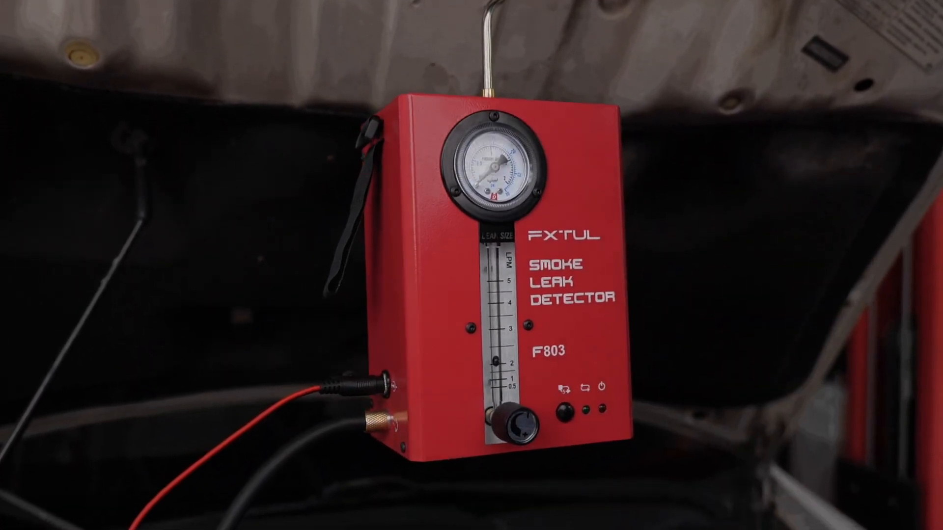 FXTUL F803 hanging upright under an open hood with its hose and power lead connected