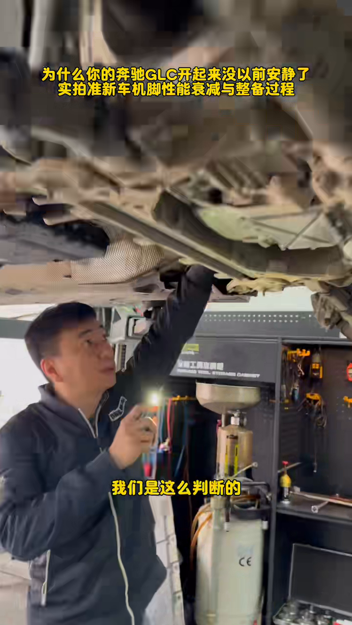 Technician inspecting the GLC260 powertrain mount area from beneath the raised vehicle