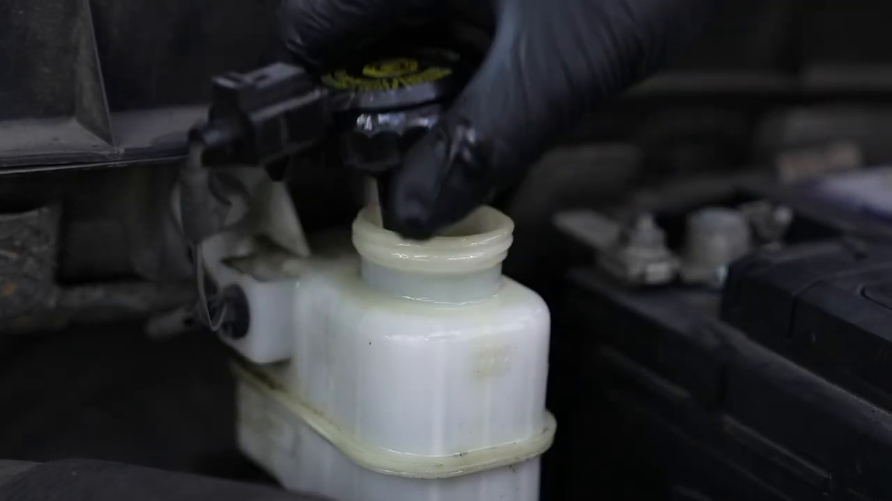 Official F109 tutorial frame showing the reservoir adapter installed on the master-cylinder brake fluid reservoir.