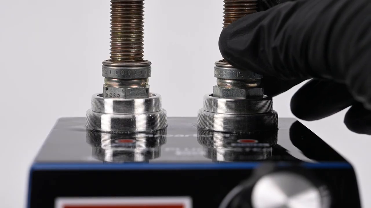Frame from the exact official H90 tutorial showing the height-adjustable socket and spark plug being fitted with the tester unpowered.