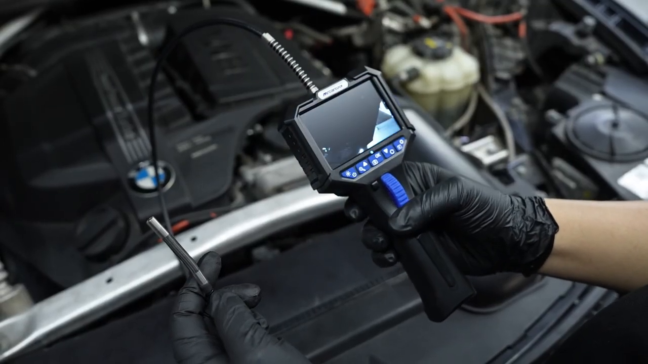 Technician checking the MRCARTOOL N150 camera and built-in display beside an open engine bay.