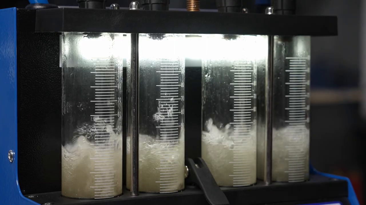 Four illuminated MRCARTOOL V308 cylinders collecting injector test fluid.