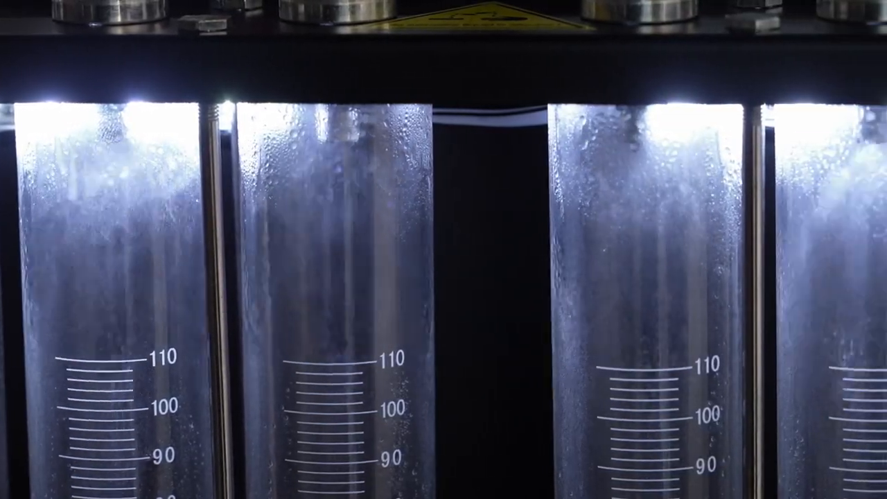 Six illuminated MRCARTOOL V310 graduated cylinders collecting injector test fluid.