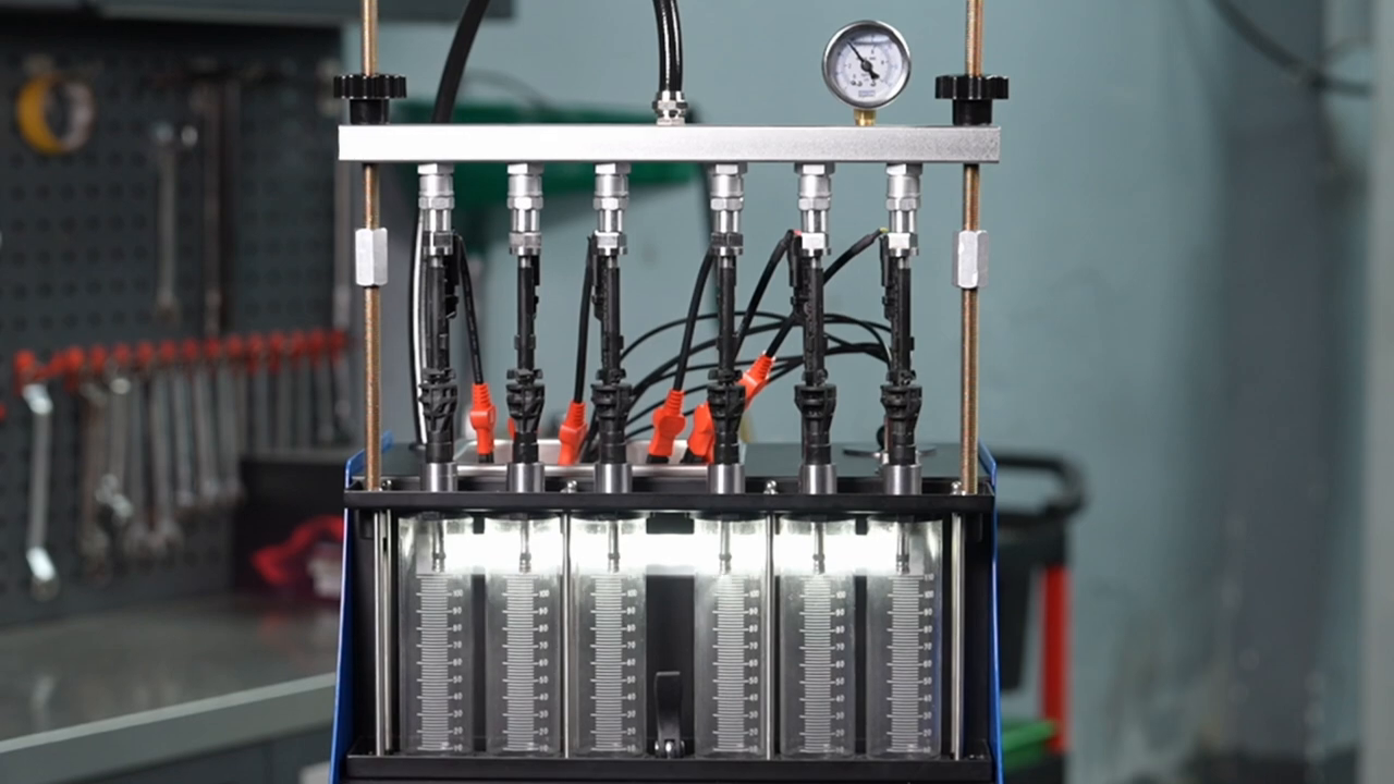 Six illuminated MRCARTOOL V311 graduated cylinders collecting injector test fluid.