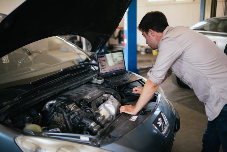 Mechanic using a laptop to diagnose a car engine