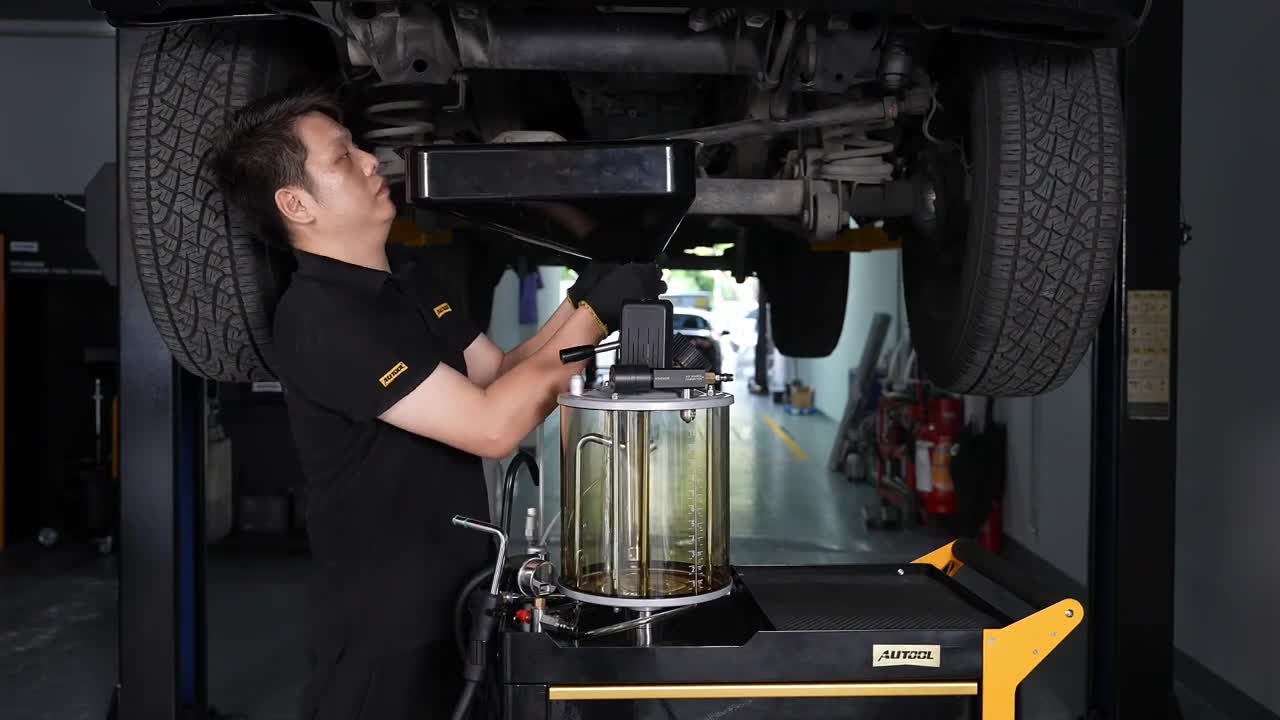 Technician positioning the AUTOOL OD760 catch pan beneath a mechanically supported vehicle