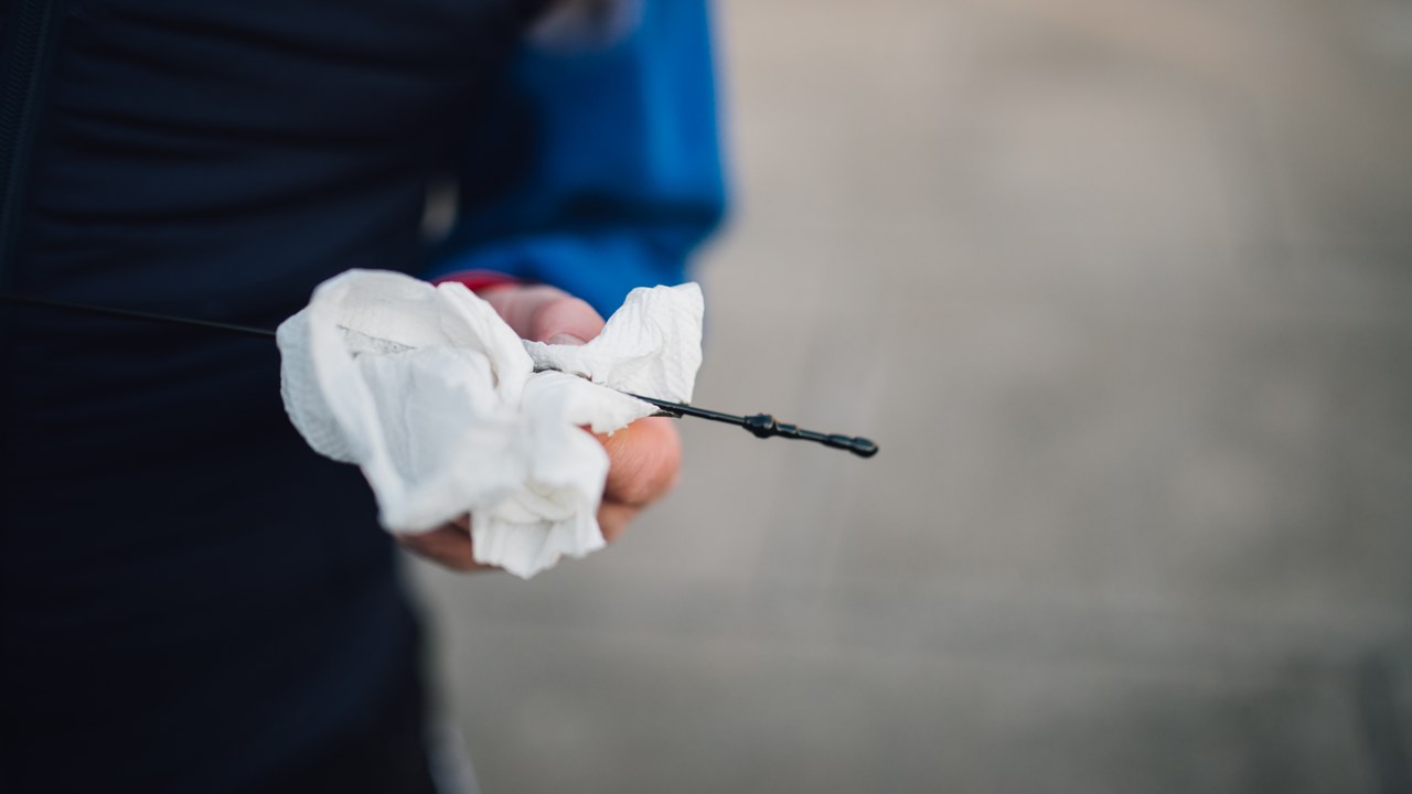 Hand wiping an engine oil dipstick before a repeat level check