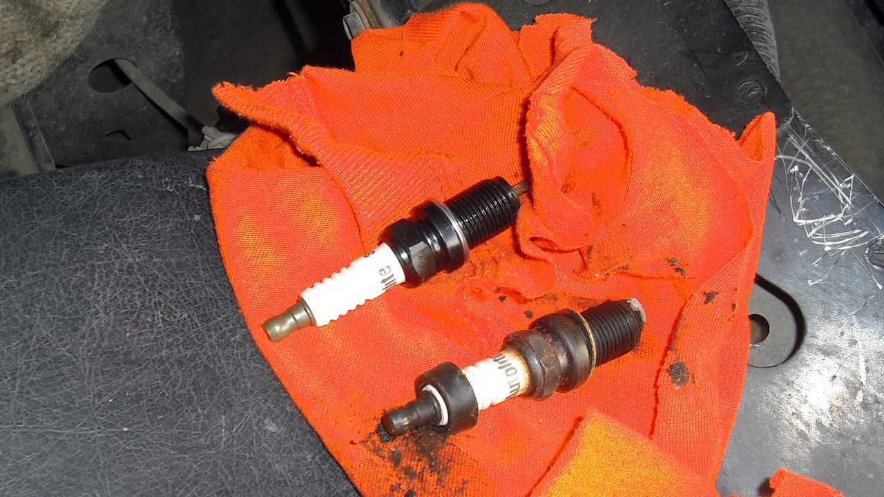 Used and replacement spark plugs arranged for visual comparison