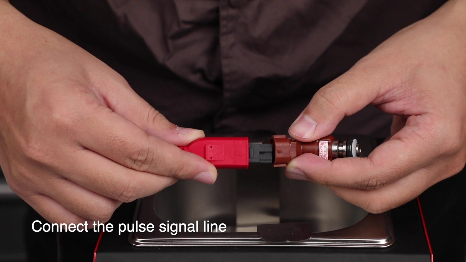 Hands aligning an UNT50 pulse signal lead connector with a removed fuel injector