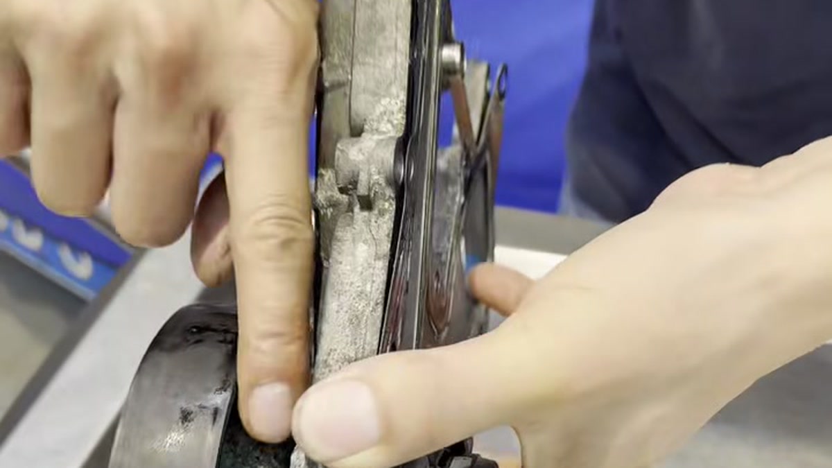 A finger points to coolant residue along the edge of a removed water pump.