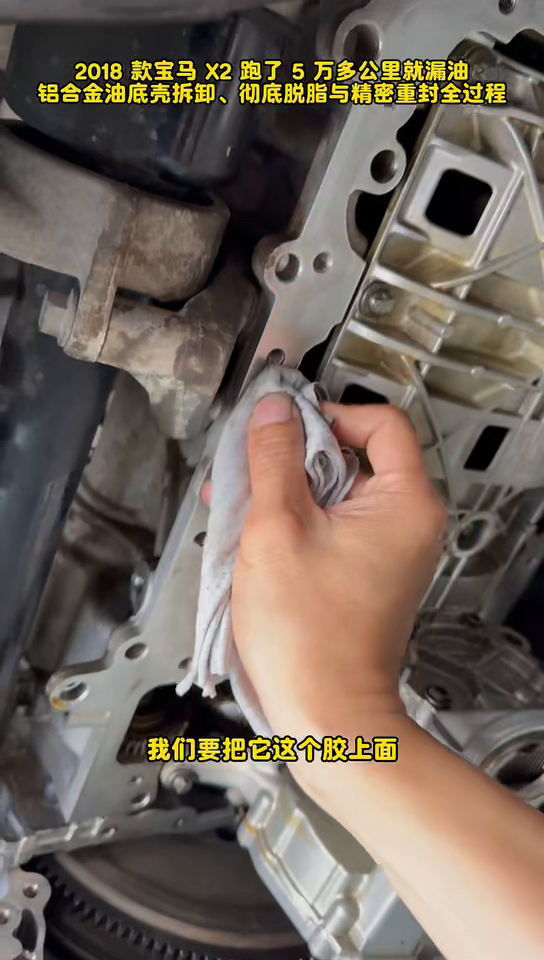 Old sealant being removed from the BMW B38 engine-side oil-pan flange.